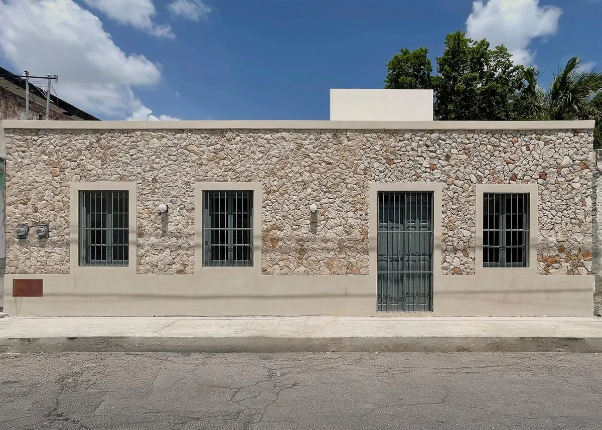 Façade after renovation: exposed stone wall with framed windows and grilles