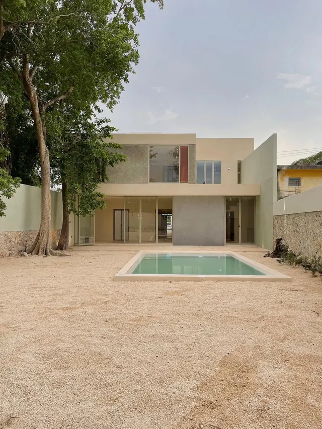 Rear of Chembech House: two-storey volume with full-height glazing, a gravel garden, trees and a pool