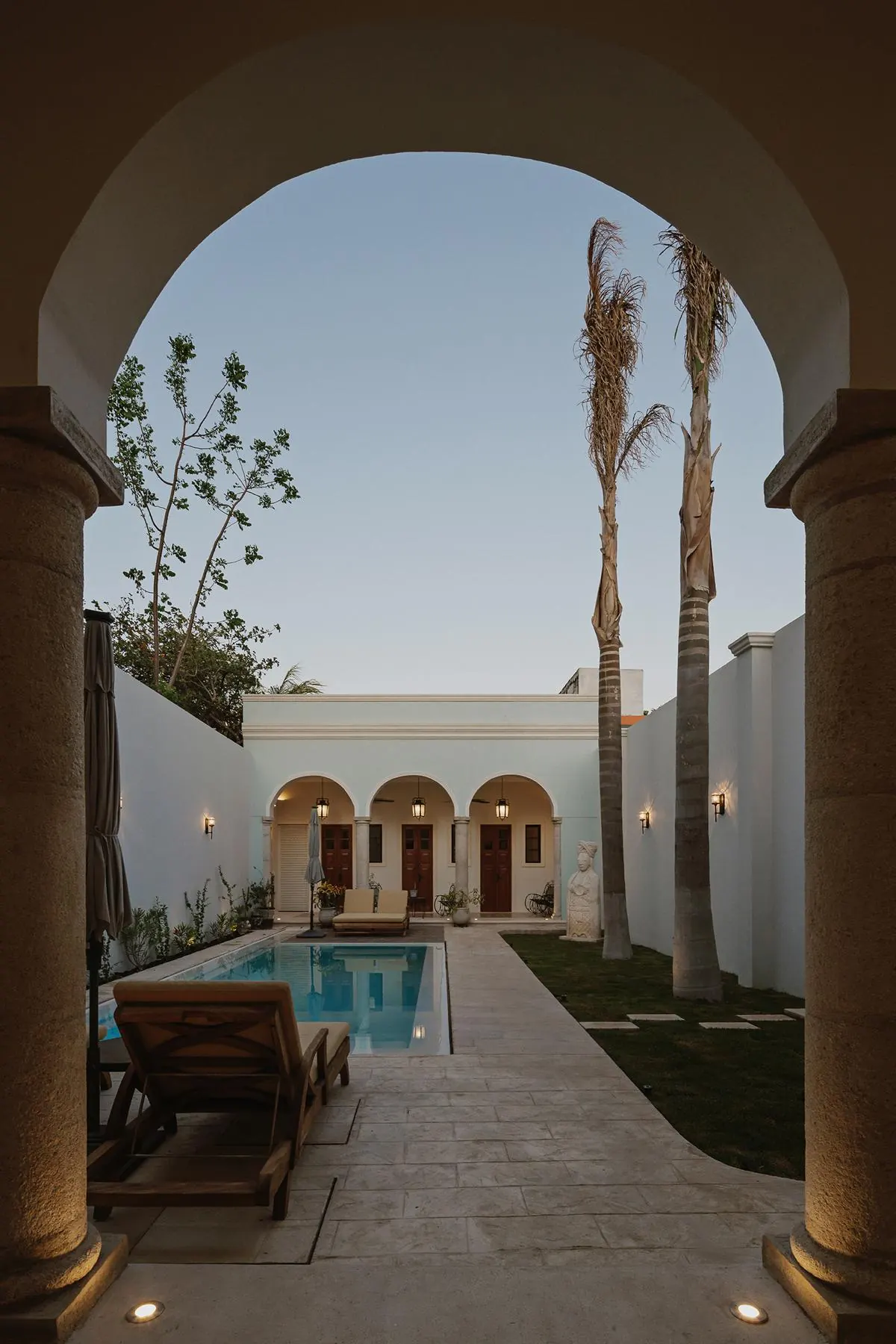 Garden and pool after renovation, seen through an arch