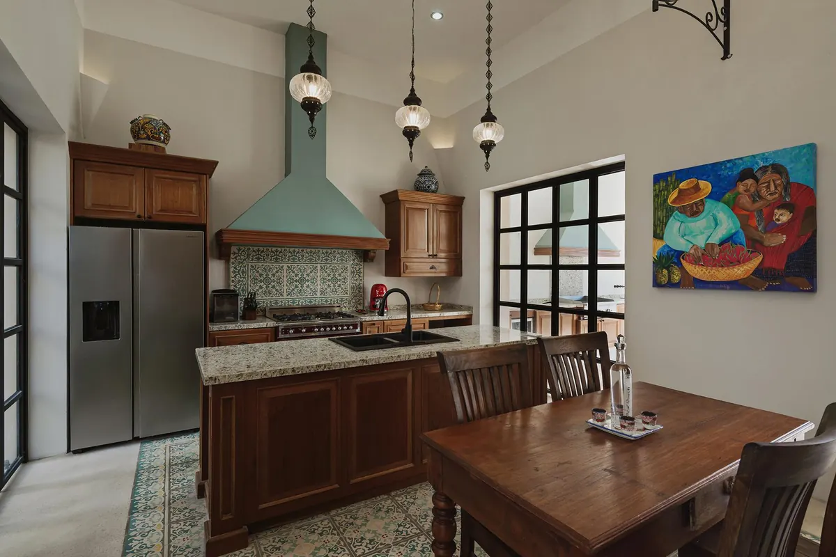 Kitchen with green hood, carved timber cabinets and pendant lamps