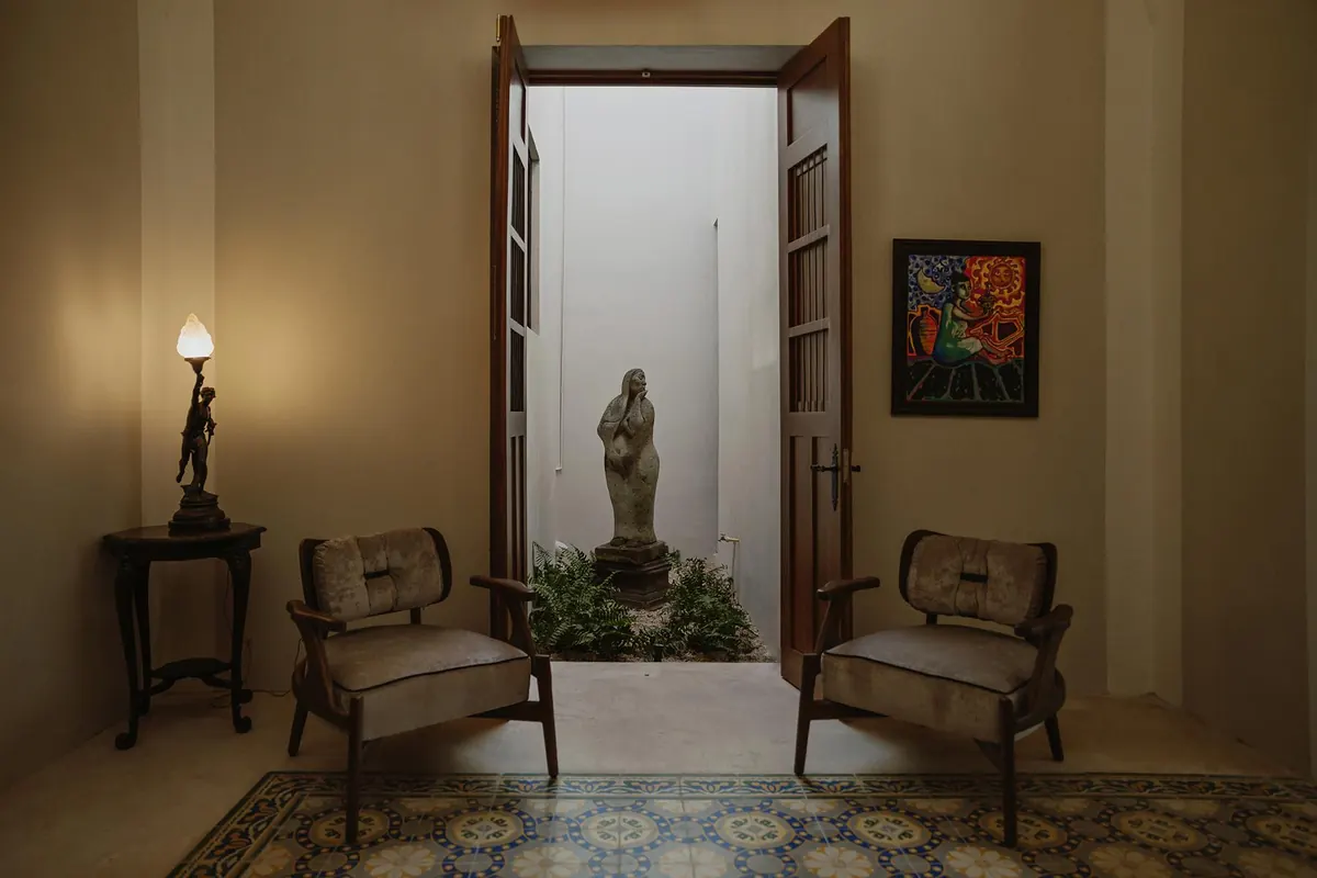 Pair of armchairs facing an open door onto a small garden with a stone sculpture
