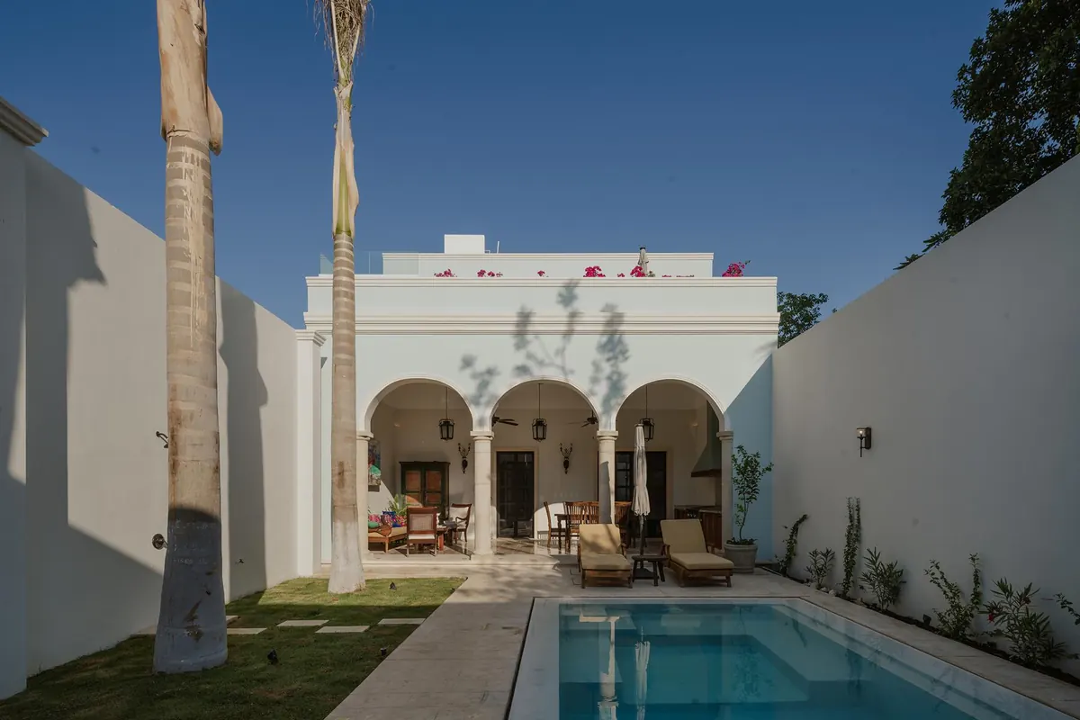 Rear garden of Casa Dos Sueños: arched terrace, two royal palms and the pool